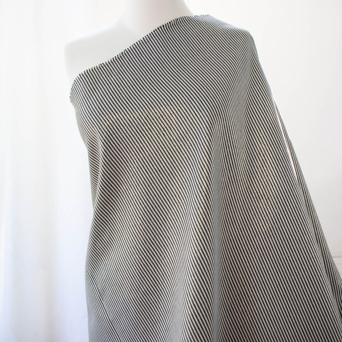 gorgeous silk ottoman suiting fabric by the yard. Featuring classic black and white horizontal stripe, enhanced by the subtle shimmer of gold metallic threads. Perfect for creating a formal gown, suiting, or a lovely lightweight coat to pair with that little black dress! Image of fabric on dressform.