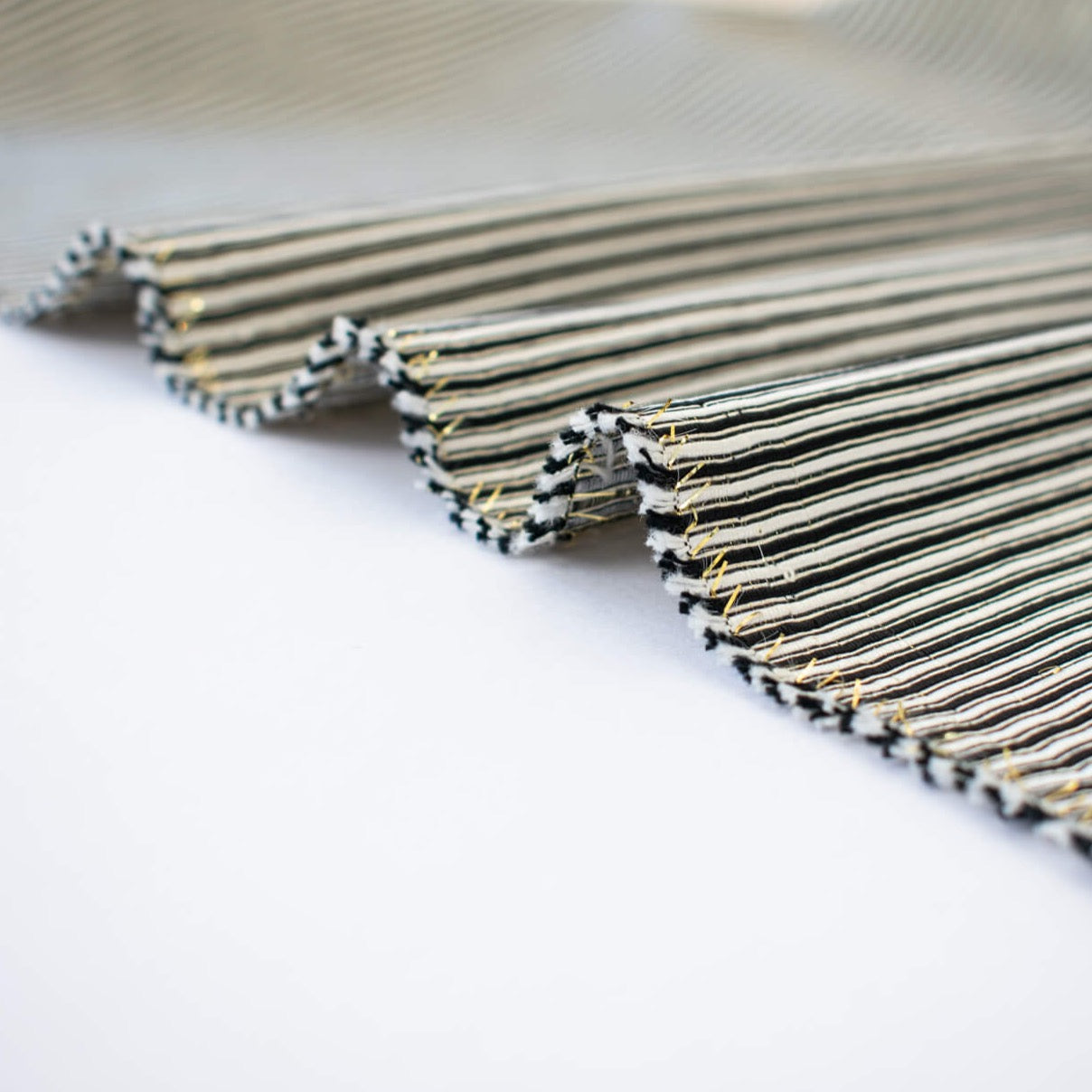 gorgeous silk ottoman suiting fabric by the yard. Featuring classic black and white horizontal stripe, enhanced by the subtle shimmer of gold metallic threads. Perfect for creating a formal gown, suiting, or a lovely lightweight coat to pair with that little black dress! Close up image of selvedge.