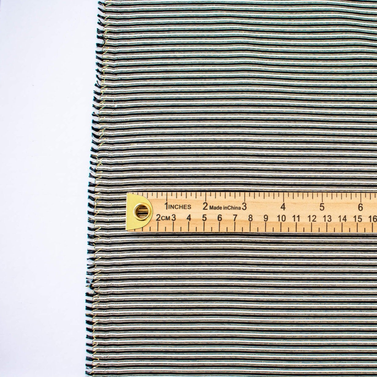 gorgeous silk ottoman suiting fabric by the yard. Featuring classic black and white horizontal stripe, enhanced by the subtle shimmer of gold metallic threads. Perfect for creating a formal gown, suiting, or a lovely lightweight coat to pair with that little black dress! Image of fabric with ruler for design scale.