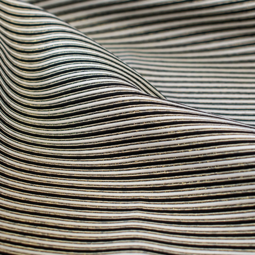 gorgeous silk ottoman suiting fabric by the yard. Featuring classic black and white horizontal stripe, enhanced by the subtle shimmer of gold metallic threads. Perfect for creating a formal gown, suiting, or a lovely lightweight coat to pair with that little black dress! Close up image.