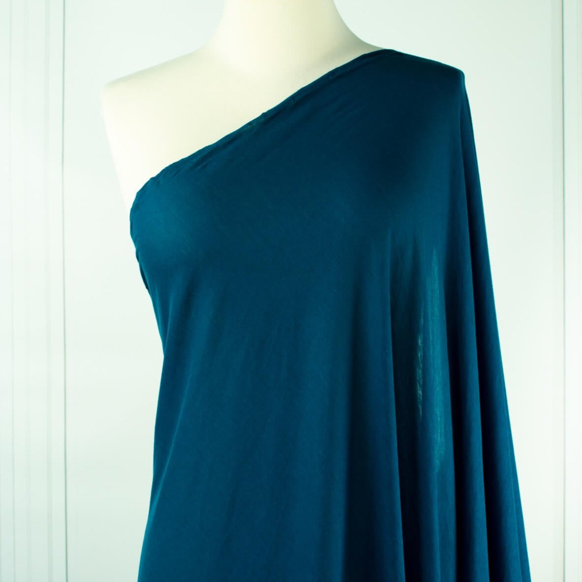 Italian Viscose Tissue Jersey designer deadstock fabric by the yard. Enjoy a bit of high-end designer British luxury! Casual, elegant, and soft, this tissue jersey has a lovely drape, thin hand, and is light and translucent. Perfect for a dress, loungewear, or T-Shirt or layering piece. Image of fabric draped on dressform.