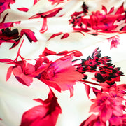Italian Floral Silk satin designer deadstock fabric by the yard. Ready to create something gorgeous with our silk satin fabric of red and pink blooms highlighted by a bit of black for drama set against a white background. This thin woven silk from the Italian mills has a smooth satiny hand and just the right amount of flow! Close up image.