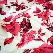 Italian Floral Silk satin designer deadstock fabric by the yard. Ready to create something gorgeous with our silk satin fabric of red and pink blooms highlighted by a bit of black for drama set against a white background. This thin woven silk from the Italian mills has a smooth satiny hand and just the right amount of flow! Image of fabric design.