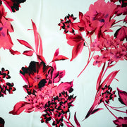 Italian Floral Silk satin designer deadstock fabric by the yard. Ready to create something gorgeous with our silk satin fabric of red and pink blooms highlighted by a bit of black for drama set against a white background. This thin woven silk from the Italian mills has a smooth satiny hand and just the right amount of flow! Image of fabric design.