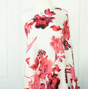 Italian Floral Silk satin designer deadstock fabric by the yard. Ready to create something gorgeous with our silk satin fabric of red and pink blooms highlighted by a bit of black for drama set against a white background. This thin woven silk from the Italian mills has a smooth satiny hand and just the right amount of flow! Image of fabric draped on dressform.