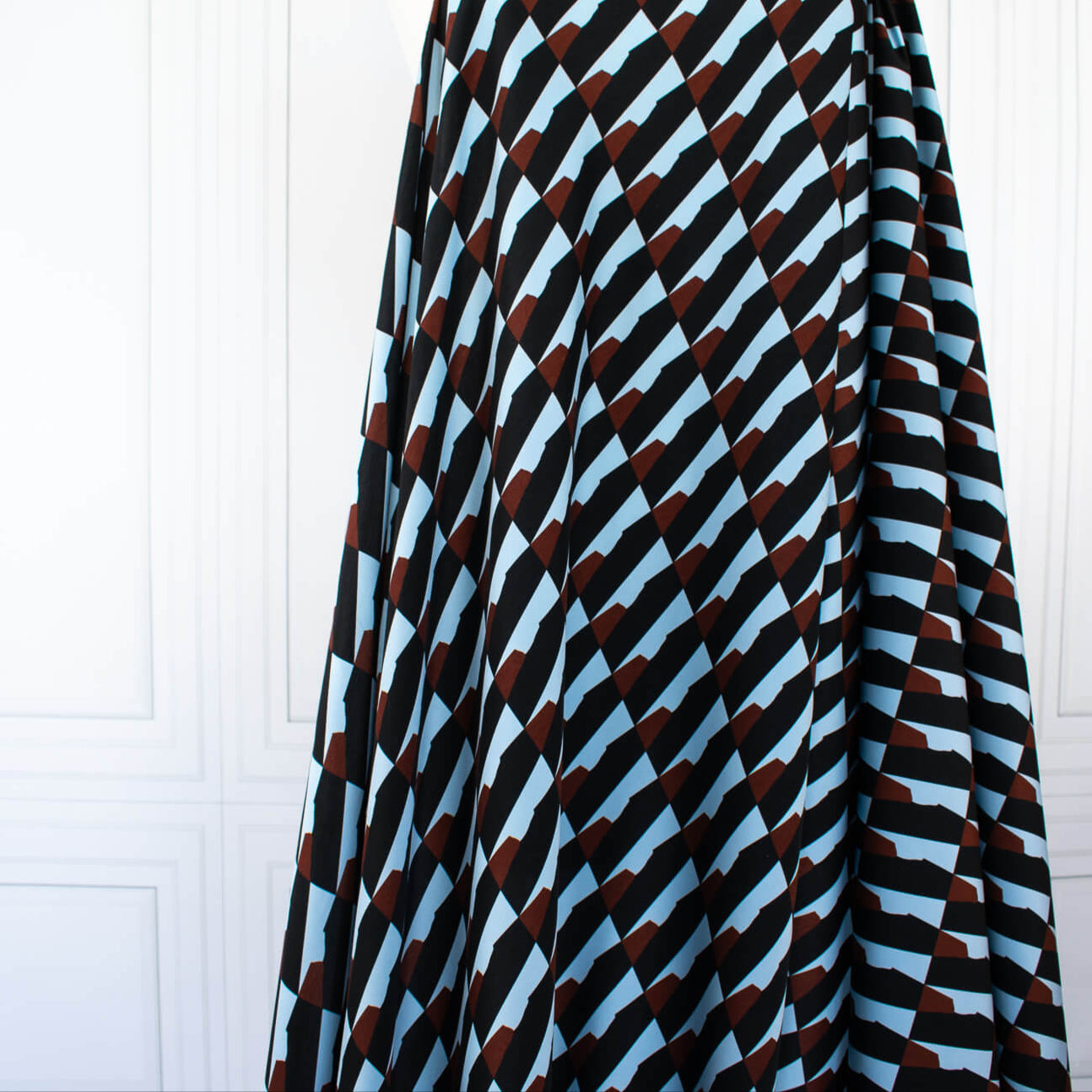 Italian Geometric Poly Satin designer deadstock fabric by the yard. From the Italian mills, a gorgeous satin with a modern palette of light blue, earthy brown and black that will elevate your next sewing project! Image of fabric drape.