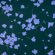 Image of fabric design. Italian Floral Viscose Crepe designer deadstock fabric by the yard. Flowers of French Blue wisp across a deep green background that evokes a breezy mood of pleasant days.