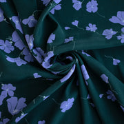 Image of fabric fullness. Italian Floral Viscose Crepe designer deadstock fabric by the yard. Flowers of French Blue wisp across a deep green background that evokes a breezy mood of pleasant days.