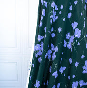 Image of fabric drape. Italian Floral Viscose Crepe designer deadstock fabric by the yard. Flowers of French Blue wisp across a deep green background that evokes a breezy mood of pleasant days.
