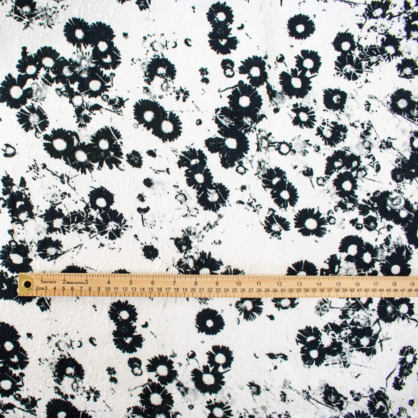 Image of couture black and white floral designer deadstock fabric by the yard! A modern floral design in black set against a creamy white is elevated by the soft "blistered" texture of this stunning jacquard. Perfect for wedding season.