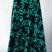 Carolina' cotton poplin designer fabric by the yard. This Italian poplin is light and billowy, perfect for sewing up tops, dresses and skirts. Made with stretch for ultimate comfort, this fabric is perfect if you want to add a touch of the exotic with its turquoise bamboo leaf print set against a black background. Image of fabric drape.
