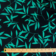 Carolina' cotton poplin designer fabric by the yard. This Italian poplin is light and billowy, perfect for sewing up tops, dresses and skirts. Made with stretch for ultimate comfort, this fabric is perfect if you want to add a touch of the exotic with its turquoise bamboo leaf print set against a black background. Image of fabric with ruler for pattern scale.