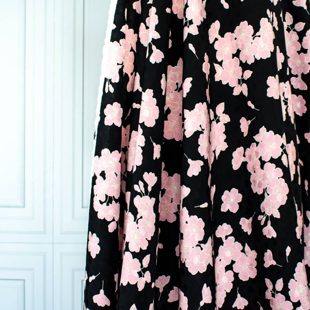 Couture Italian Viscose Floral Jacquard - 'All My Heart'! This stunning designer deadstock fabric by the yard features a gorgeous black base with delicate pink florals and ivory accents. Plus, playful and trending jacquard hearts add a touch of whimsy. 
Featuring a nice drape that falls away from the body and slightly textured hand, you'll find this fabric is perfect for formal attire or a little something special.  Image of fabric drape.