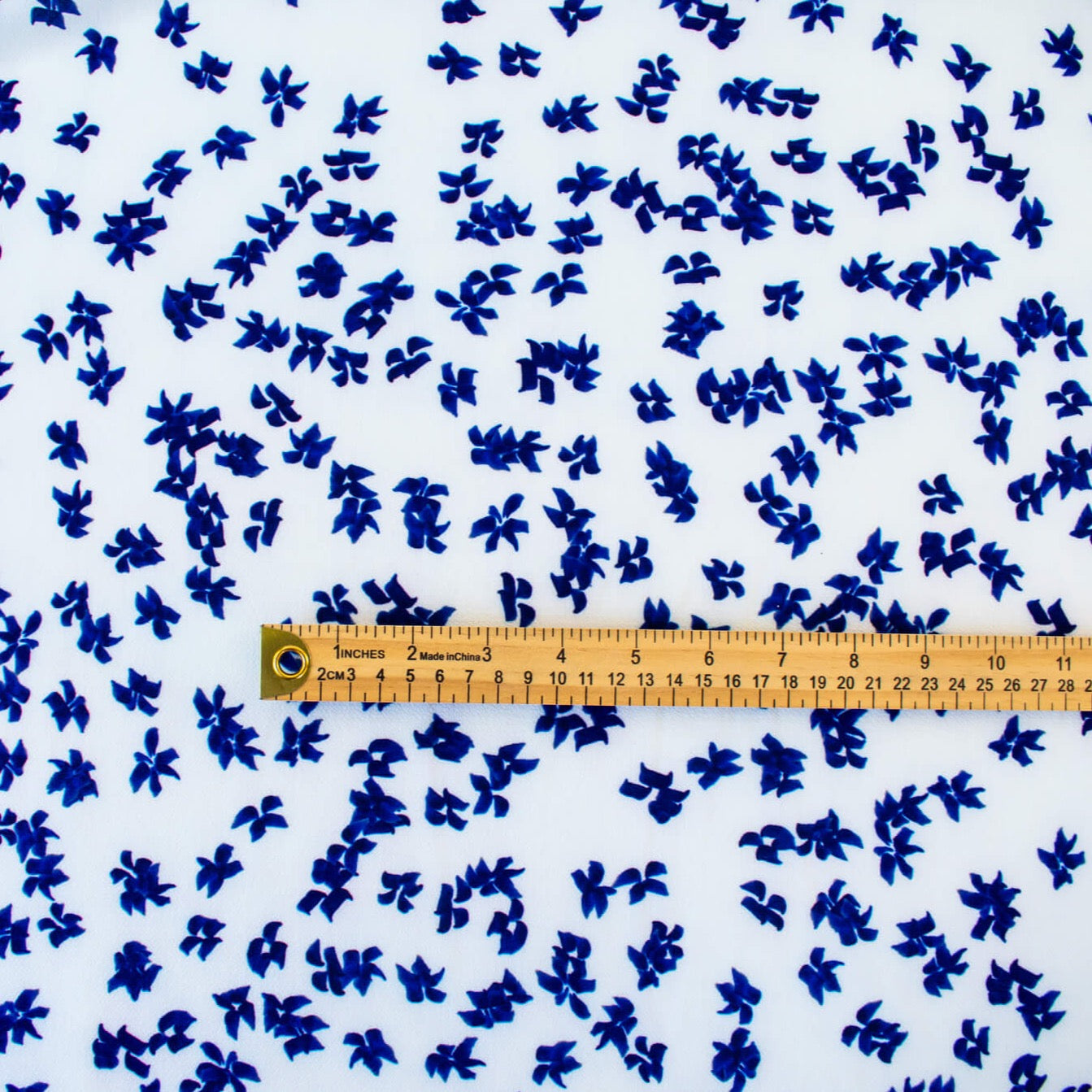 Image of fabric design with ruler for scale. Couture, Italian, blue and white floral crepe deadstock fabric by the yard. Sourced from a Los Angeles designer of ready-to-wear and bridal pieces and a favorite among some of Hollywoods A-List stars!