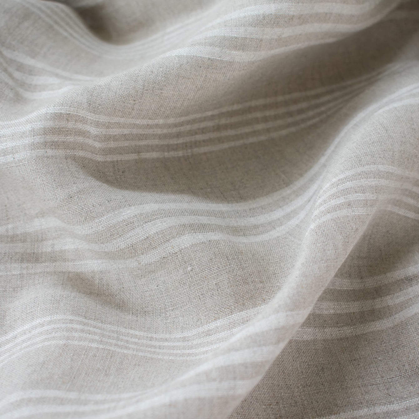 Experience the luxury of European linen fabric in a classic horizontal stripe. This medium weight linen would make a stunning jacket, skirt or pant. Featuring a wide width, textured hand, and sets of wide and narrow off white stripes. Photo of fabric