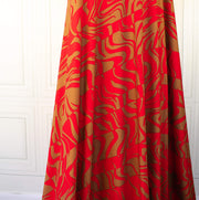 Italian Single Viscose Jersey Red and Caramel Modern Print fabric by the yard. A gorgeous vibrant knit that is sure to capture compliments. We love this combination of red and caramel brown tones in this modern jersey knit fabric. The printed design has a bit of animal print edge in a stripe like pattern.  Image of fabric drape.