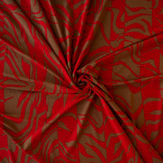 Italian Single Viscose Jersey Red and Caramel Modern Print fabric by the yard. A gorgeous vibrant knit that is sure to capture compliments. We love this combination of red and caramel brown tones in this modern jersey knit fabric. The printed design has a bit of animal print edge in a stripe like pattern.  Image of fabric fullness.