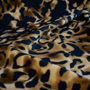 Italian Animal Print Wool Blend Jersey knit fabric by the yard. Shades of gold and cream flow against dramatic coal a bits of blue to create a vibrant and sophisticated animal print design. This would make a lovely wrap style long cardigan, a bold fitted sheath dress, or pencil skirt. Close up image.