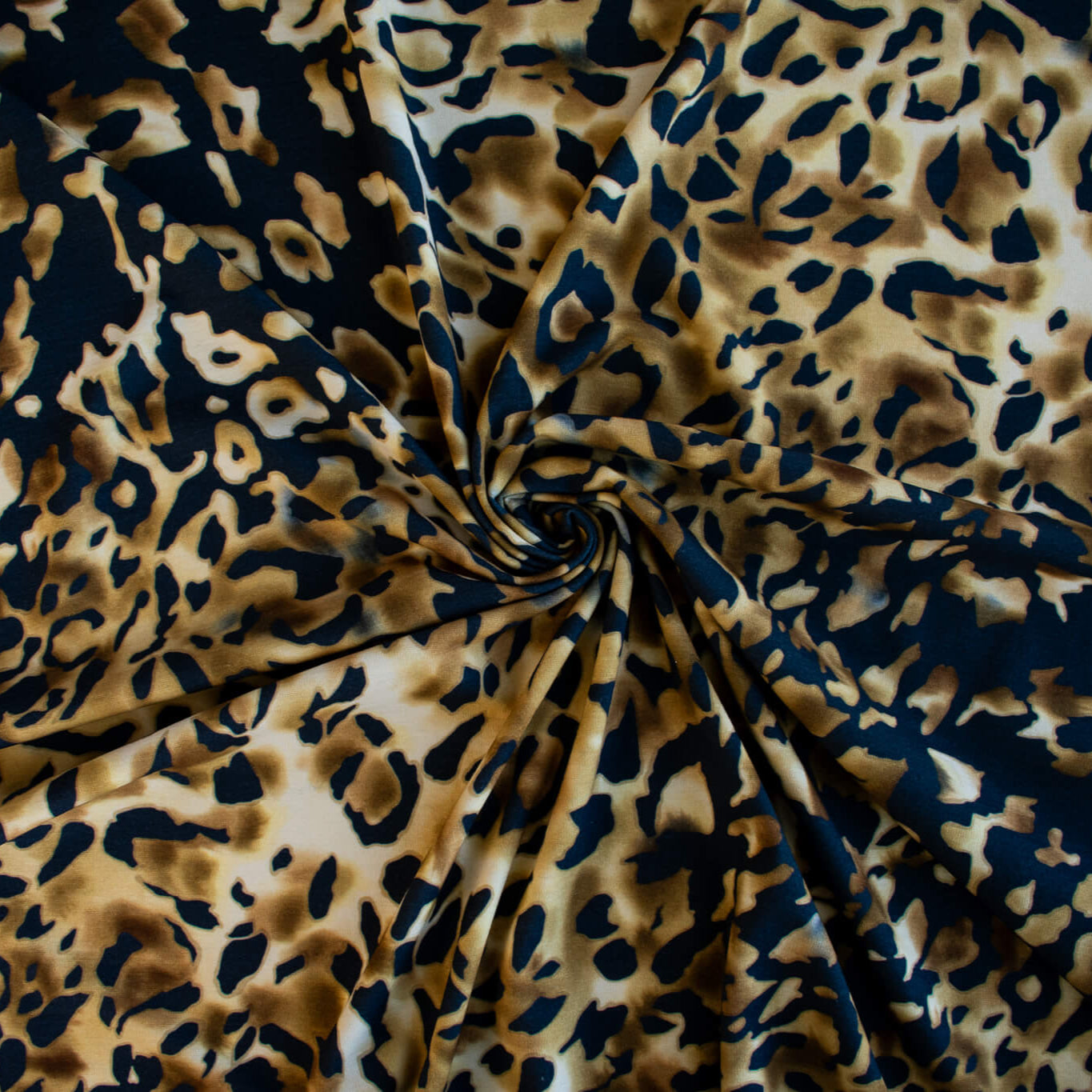 Italian Animal Print Wool Blend Jersey knit fabric by the yard. Shades of gold and cream flow against dramatic coal a bits of blue to create a vibrant and sophisticated animal print design. This would make a lovely wrap style long cardigan, a bold fitted sheath dress, or pencil skirt. Image of fabric fullness.