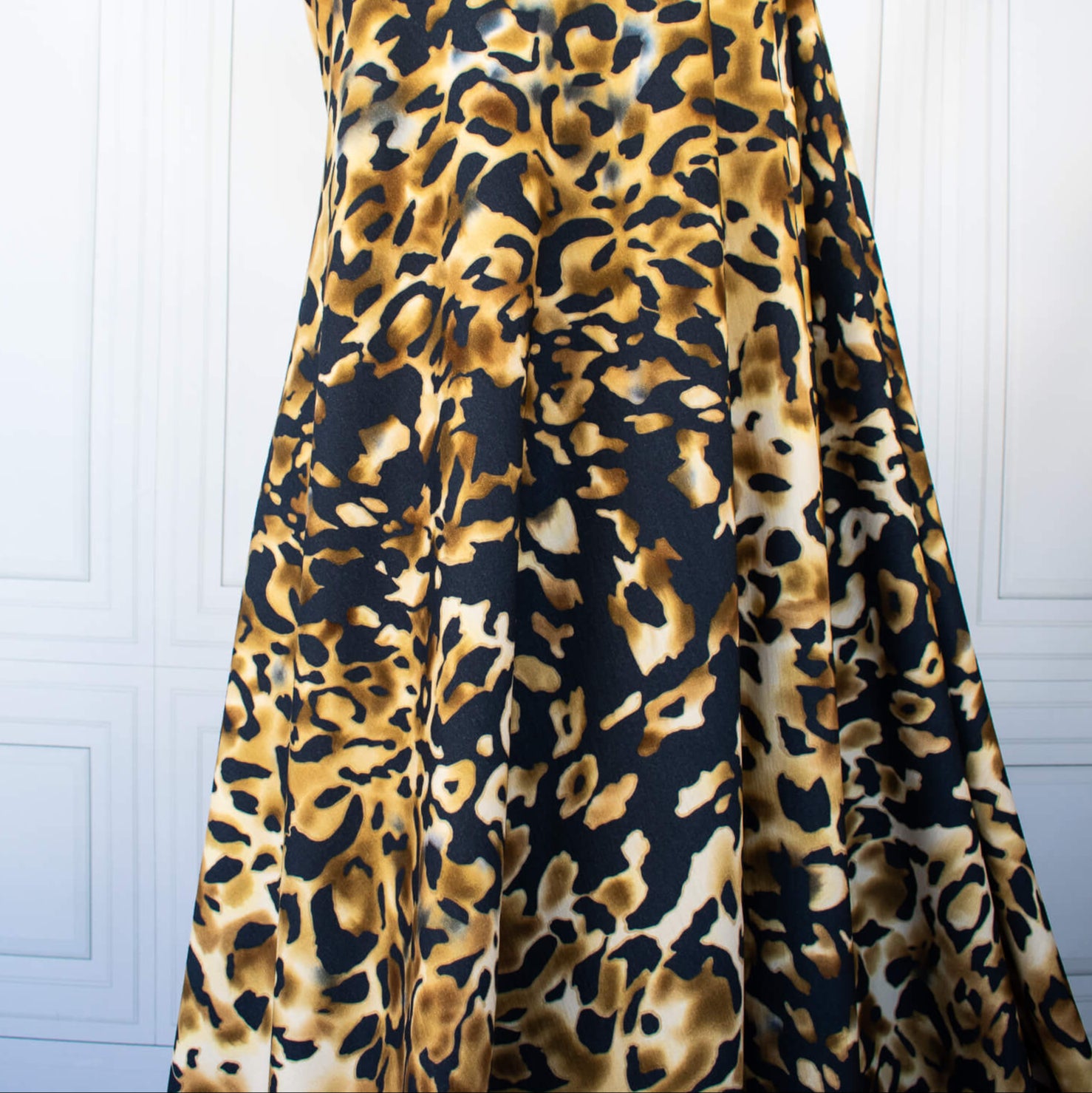 Italian Animal Print Wool Blend Jersey knit fabric by the yard. Shades of gold and cream flow against dramatic coal a bits of blue to create a vibrant and sophisticated animal print design. This would make a lovely wrap style long cardigan, a bold fitted sheath dress, or pencil skirt. Image of fabric drape.
