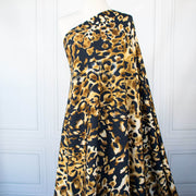 Italian Animal Print Wool Blend Jersey knit fabric by the yard. Shades of gold and cream flow against dramatic coal a bits of blue to create a vibrant and sophisticated animal print design. This would make a lovely wrap style long cardigan, a bold fitted sheath dress, or pencil skirt. Image of fabric draped on dressform.