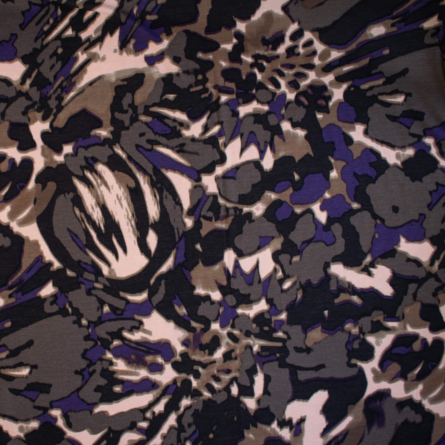 Italian Modern Floral Single Jersey Wool blend fabric by the yard. Gorgeous modern floral print perfect for transitioning to warmer months. This wool blend jersey in shades of brown, light pink, purple and black has a soft hand a beautiful drape. Whether you are creating a T-shirt or something a bit fancier, you're going to love how this fabric feels against your skin. Image of fabric design.