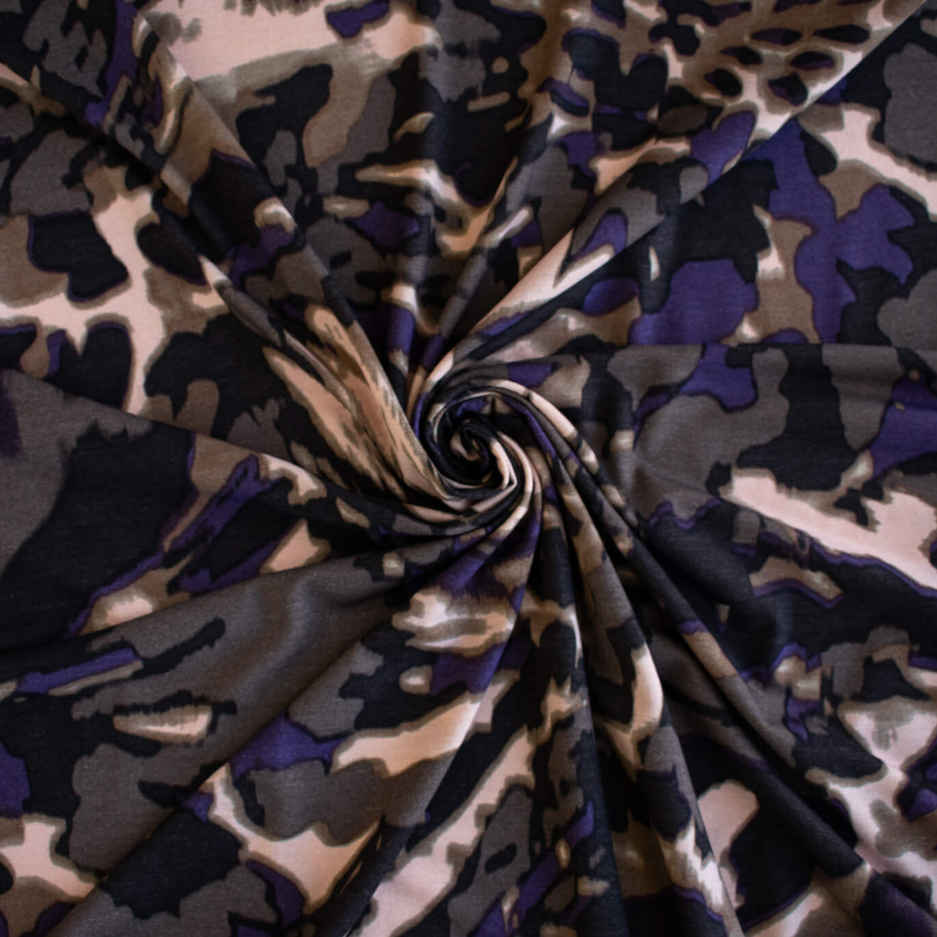 Italian Modern Floral Single Jersey Wool blend fabric by the yard. Gorgeous modern floral print perfect for transitioning to warmer months. This wool blend jersey in shades of brown, light pink, purple and black has a soft hand a beautiful drape. Whether you are creating a T-shirt or something a bit fancier, you're going to love how this fabric feels against your skin. Image of fabric fullness.