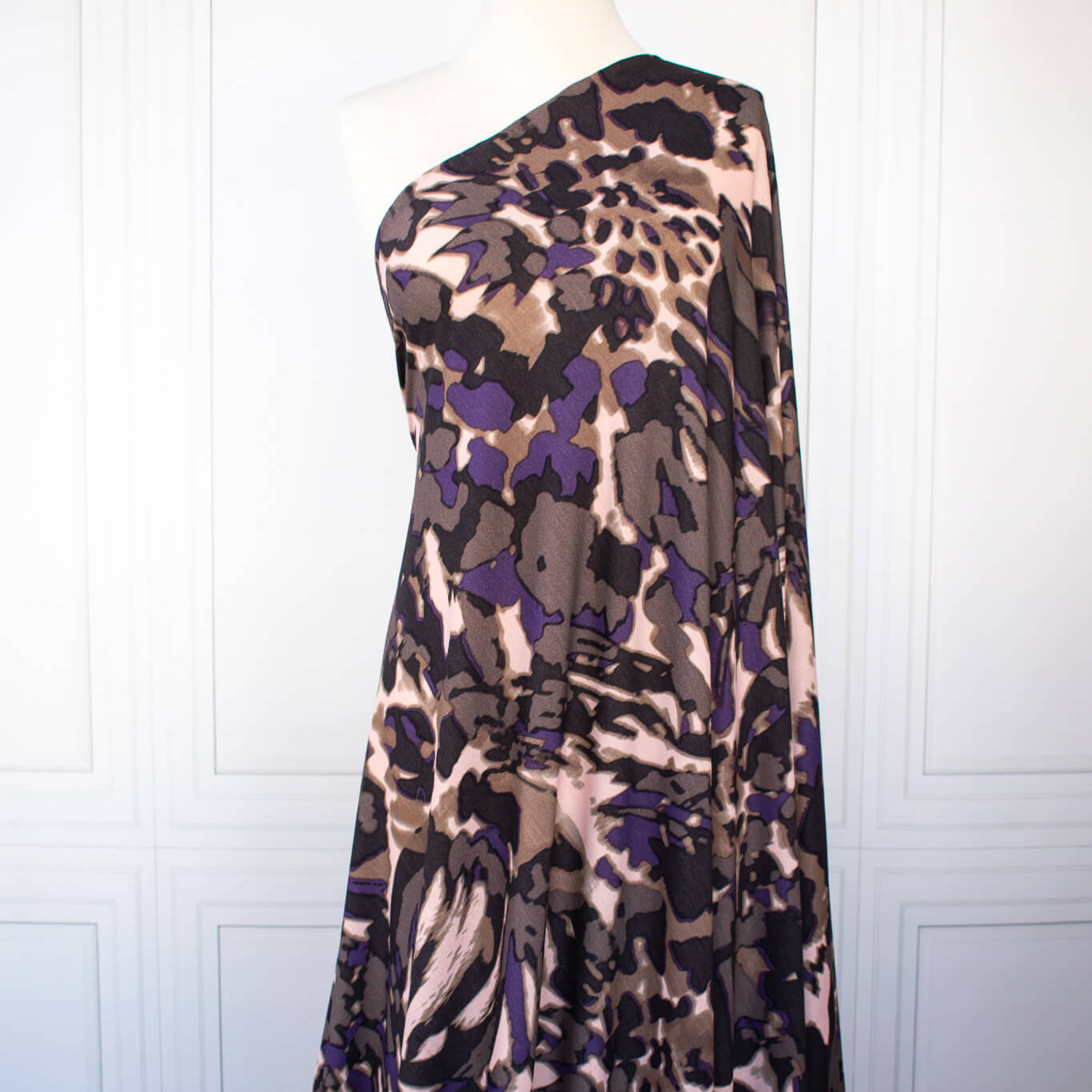 Italian Modern Floral Single Jersey Wool blend fabric by the yard. Gorgeous modern floral print perfect for transitioning to warmer months. This wool blend jersey in shades of brown, light pink, purple and black has a soft hand a beautiful drape. Whether you are creating a T-shirt or something a bit fancier, you're going to love how this fabric feels against your skin. Long image of fabric draped on dressform.