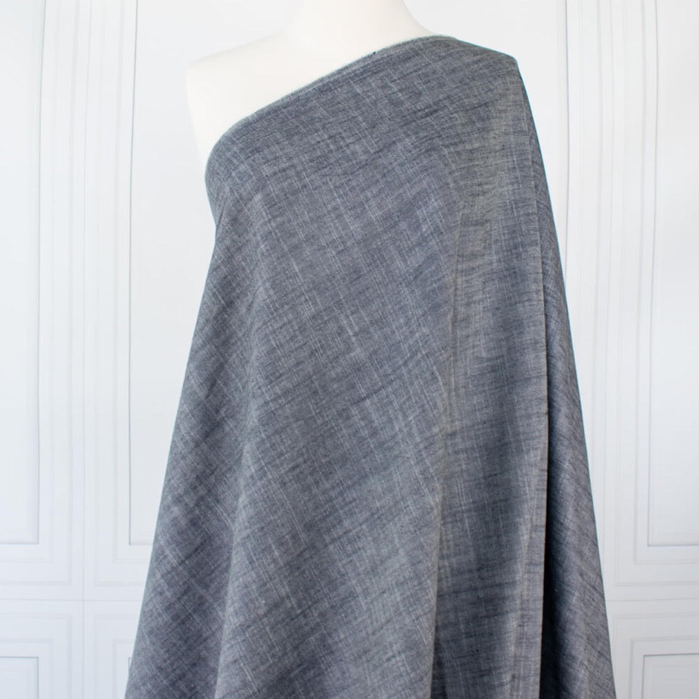 Stay cool and look amazing while you enjoy the breathability and sustainability of Tencel and all you love about linen in one gorgeous dark indigo fabric.   On the lighter side of a mid-weight with a beautiful sheen, nice drape, and softly textured hand you'll look 'Tres Chic'!  Vertical image of fabric draped on dressform.