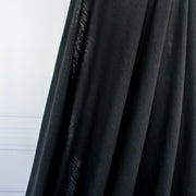 NYC High-End Designer Black Cotton Jersey Knit fabric by the yard. This deadstock fabric is the perfect sustainable choice for creating soft, flowy pieces that are both stylish and playful. It has a soft hand and translucent quality, and the extra wide width allows for versatile designs. Image of fabric drape.