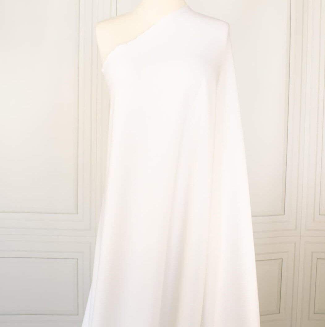 High-End Designer Pearl White Ponte Knit fabric by the yard. This Los Angeles designer has a knack for finding quality fabrics. This designer deadstock Ponte is soft with a nice drape that falls moderately close to the body. You'll fall in love with the comfort! Image of fabric on dress form.