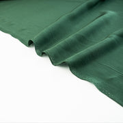 00% Silk Crepe de Chine fabric by the yard in Fern Green. Soft and fluid, this semi-textured fabric offers a beautiful drape and the luxury of silk. Image of selvedge.