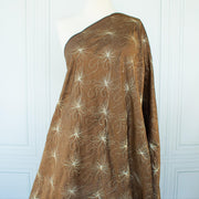 100% silk shantung fabric by the yard featuring a metallic embroidered floral design in a modern and playful hand-drawn style. In a rich hazelnut brown hue, this fabric offers a crisp and light textured hand, with a soft sheen for added elegance. Image of fabric on dressform.