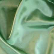 NYC Designer Polyester Satin designer deadstock fabric by the yard. Shimmery satin in a serene spring green is sophisticated and eye catching!  This opaque, tightly woven fabric falls moderately away from the body. Close up image.