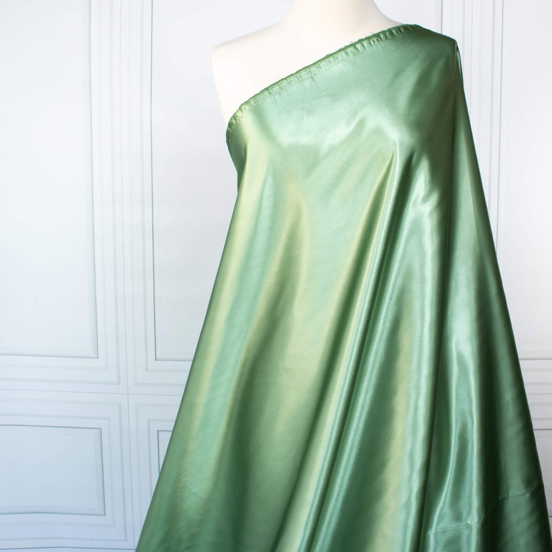 NYC Designer Polyester Satin designer deadstock fabric by the yard. Shimmery satin in a serene spring green is sophisticated and eye catching!  This opaque, tightly woven fabric falls moderately away from the body. Image of fabric drape.