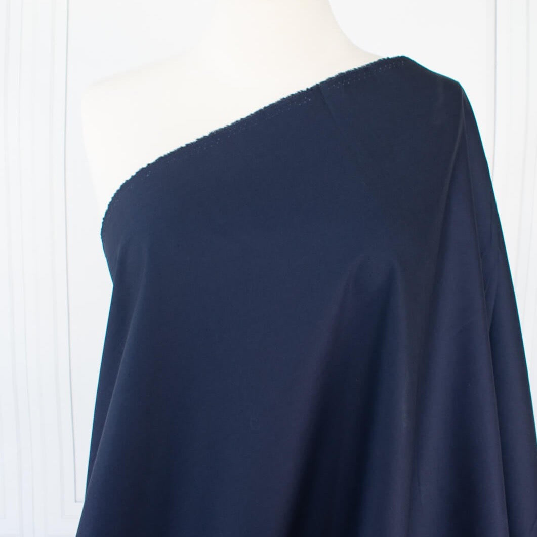 New York Designer deadstock shirting fabric by the yard. A must-have for any fashionista, this classic navy blue semi-crisp shirting with a soft, textured hand is a versatile staple. Perfect for any season and pairs well with any color. Get creative and mix and match to your heart's content!  Image of fabric draped on dressform.