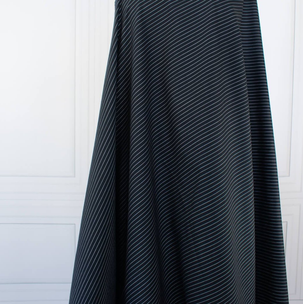 NYC Designer Dark Navy/White Striped Cotton/Spandex Shirting fabric by the yard in a midnight blue is a perfect staple when building your wardrobe pieces. This designer deadstock fabric boasts a soft and smooth hand, is tightly woven and enhanced with a touch of stretch.  Image of fabric drape reflecting how it will fall on the body.