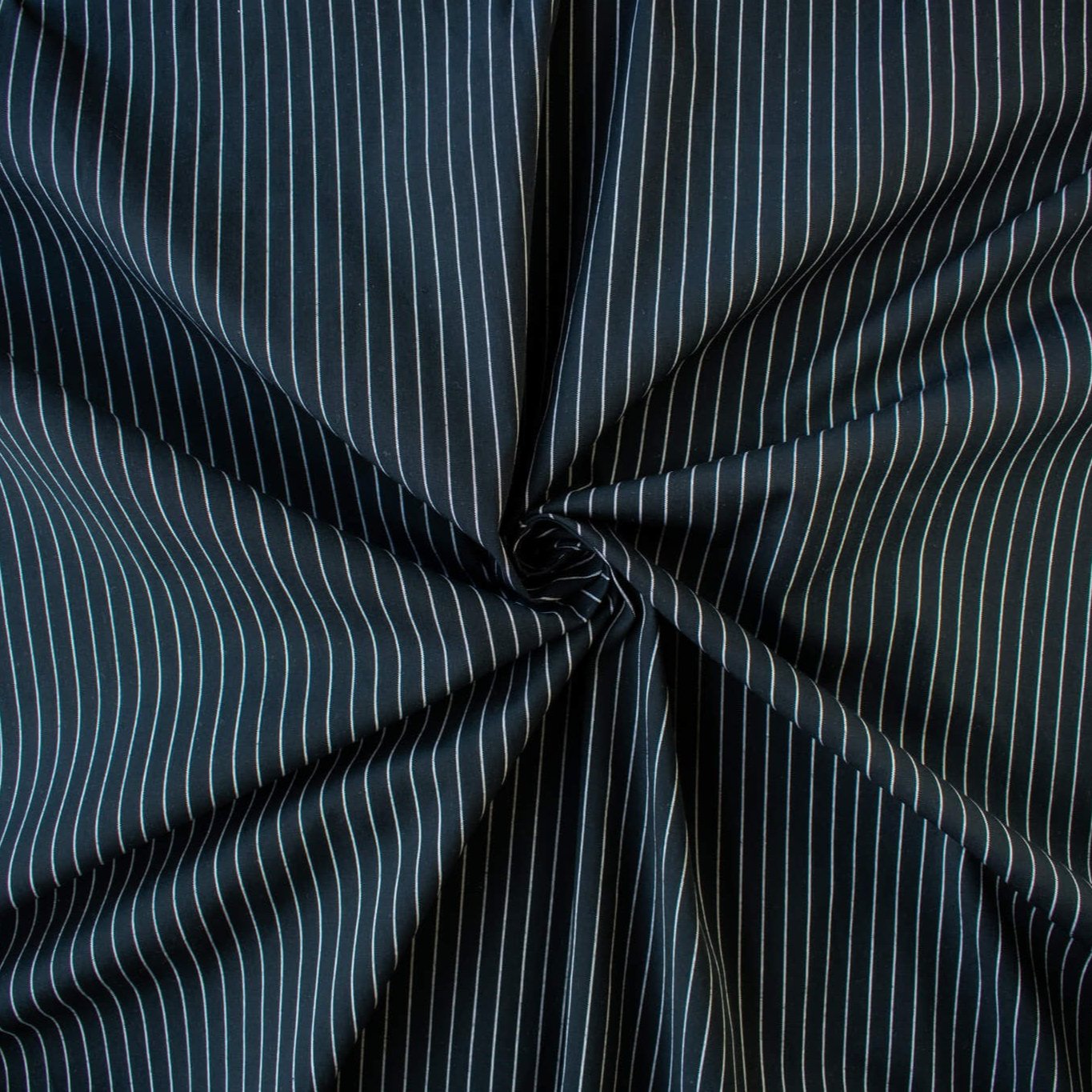 NYC Designer Dark Navy/White Striped Cotton/Spandex Shirting fabric by the yard in a midnight blue is a perfect staple when building your wardrobe pieces. This designer deadstock fabric boasts a soft and smooth hand, is tightly woven and enhanced with a touch of stretch.  Image of fabric fullness.