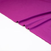 Designer ITY Solid Jersey Knit designer deadstock fabric by the yard. Perfect for travelwear, this ITY is universally flattering in a gorgeous light Orchid purple color. Image of selvedge.
