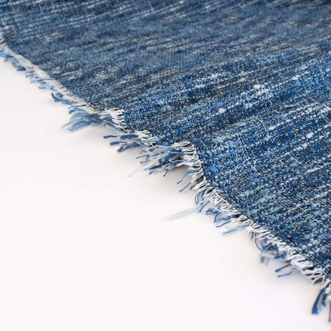 A beautifully soft NYC Designer Boucle suiting fabric by the yard that can be paired with sophisticated solids or your favorite denim. Varying shades of blue and alabaster yarns make this boucle extra special. Enjoy creating your next make with style and comfort. Image of fabric selvedge.