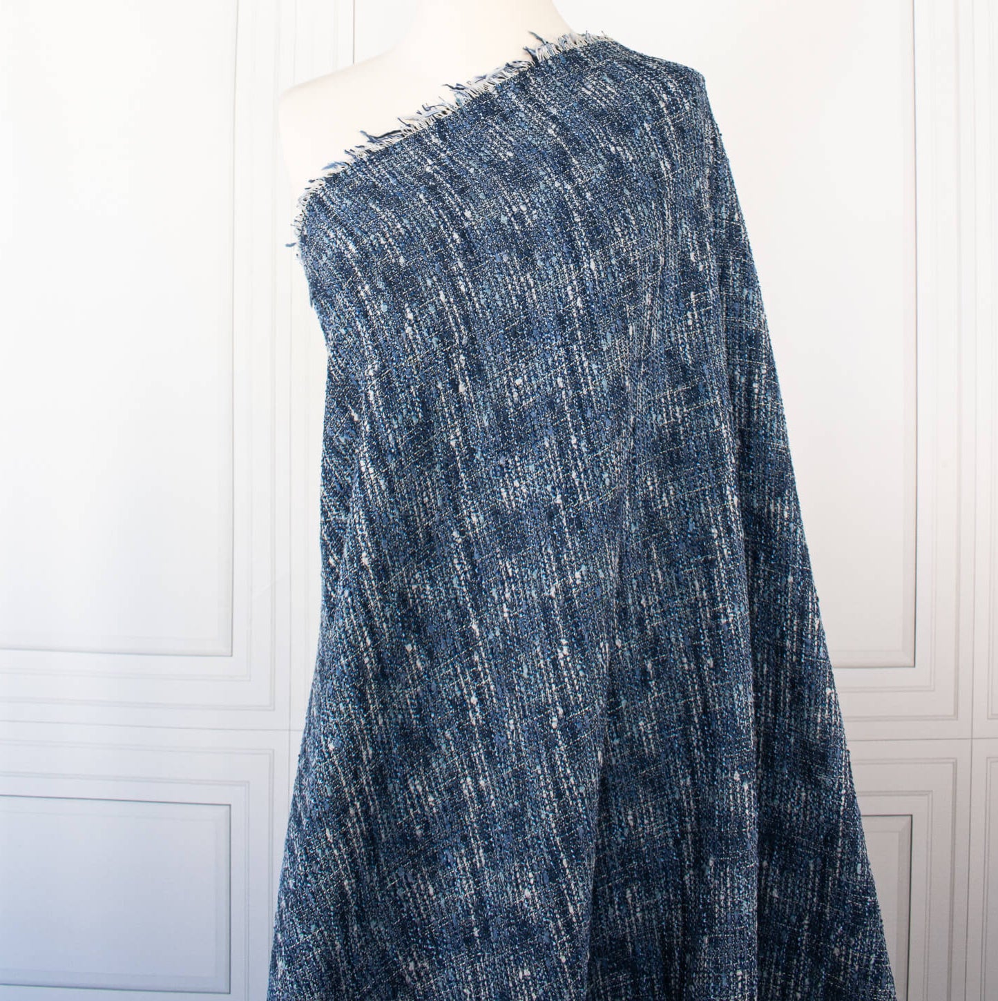 A beautifully soft NYC Designer Boucle suiting fabric by the yard that can be paired with sophisticated solids or your favorite denim. Varying shades of blue and alabaster yarns make this boucle extra special. Enjoy creating your next make with style and comfort. Image of fabric draped on dressform.
