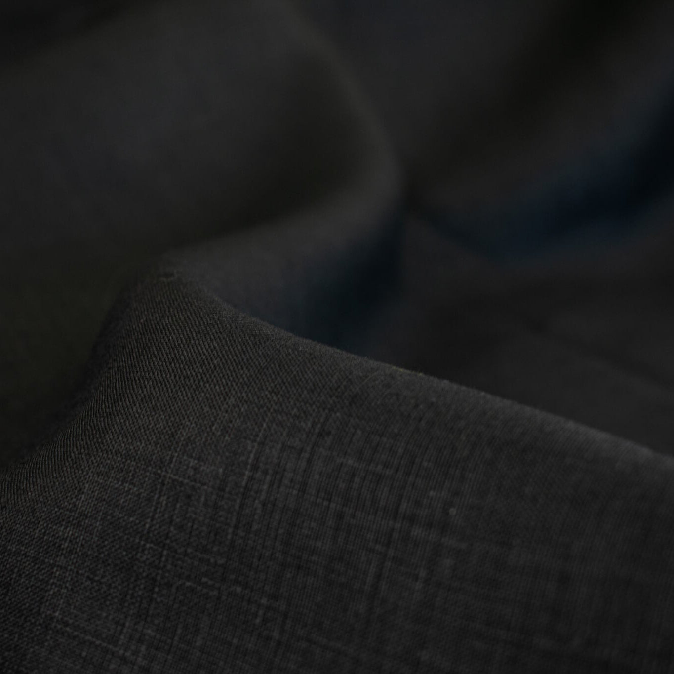 Italian, rich black 100% Linen fabric by the yard in a lovely mid-weight. The soft, crisp, and semi-textured hand of this fabric is perfect for creating sophisticated vests, dresses, suits, and skirts. This breathable fabric is perfect for warmer weather, making it a must-have for any fashion enthusiast. Close up image of fabric weave.