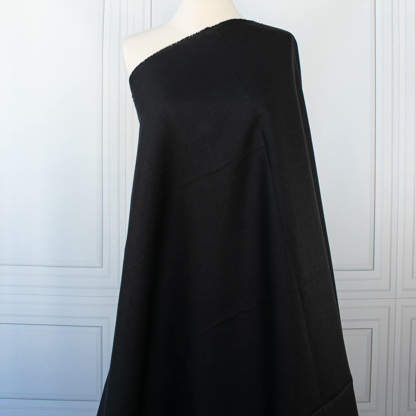 Italian, rich black 100% Linen fabric by the yard in a lovely mid-weight. The soft, crisp, and semi-textured hand of this fabric is perfect for creating sophisticated vests, dresses, suits, and skirts. This breathable fabric is perfect for warmer weather, making it a must-have for any fashion enthusiast. Image of fabric on dressform.