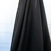 Italian, rich black 100% Linen fabric by the yard in a lovely mid-weight. The soft, crisp, and semi-textured hand of this fabric is perfect for creating sophisticated vests, dresses, suits, and skirts. This breathable fabric is perfect for warmer weather, making it a must-have for any fashion enthusiast. Image of fabric drape.