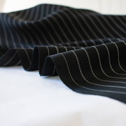 Gorgeous Couture Designer 4-Ply Silk Black with a white vertical double pinstripe, this premium medium weight silk has a soft sheen and gentle drape. A fine smooth hand feels buttery on the skin, perfect for a wide leg pant, vest, jacket or dress! Close up image of selvedge.
