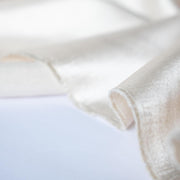 Designer dead stock fabric in a silky champagne polyester charmeuse. Canadian designer. Image of selvedge edge.