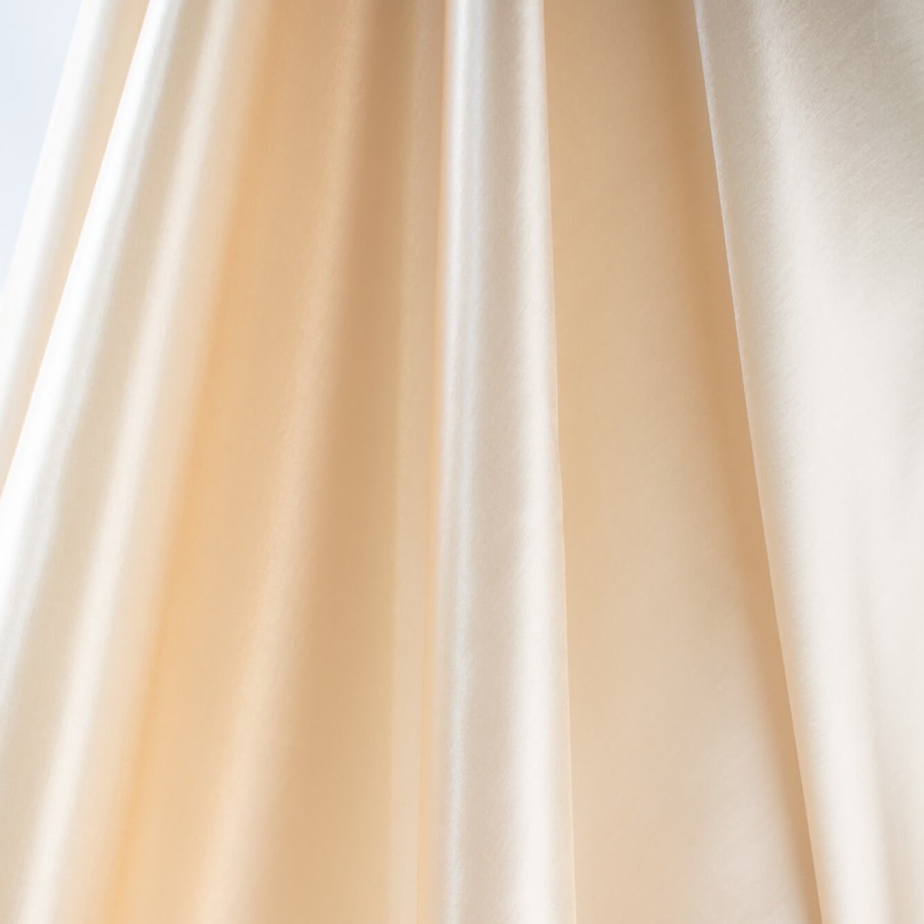 Designer dead stock fabric in a silky champagne polyester charmeuse. Canadian designer. Image of fabric drape.  Edit alt text