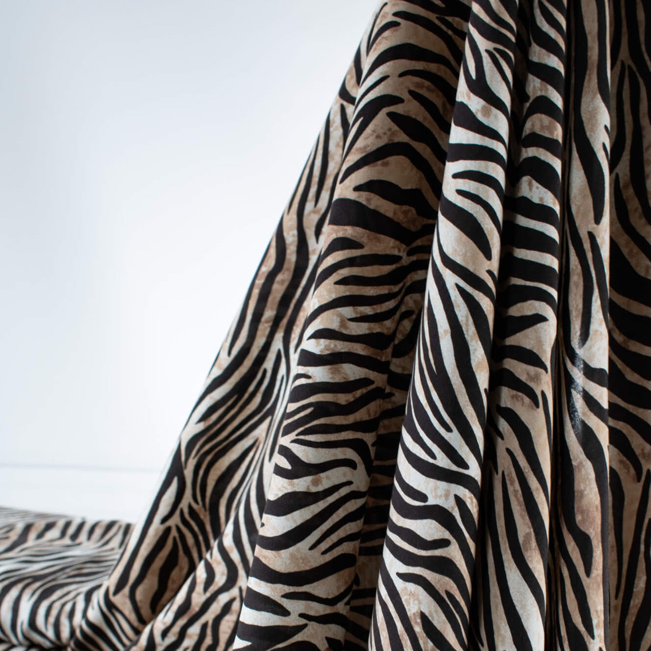 Famous Designer Rayon Challis flowy and soft animal print in tan white and black. Photo depicts fabric drape.
