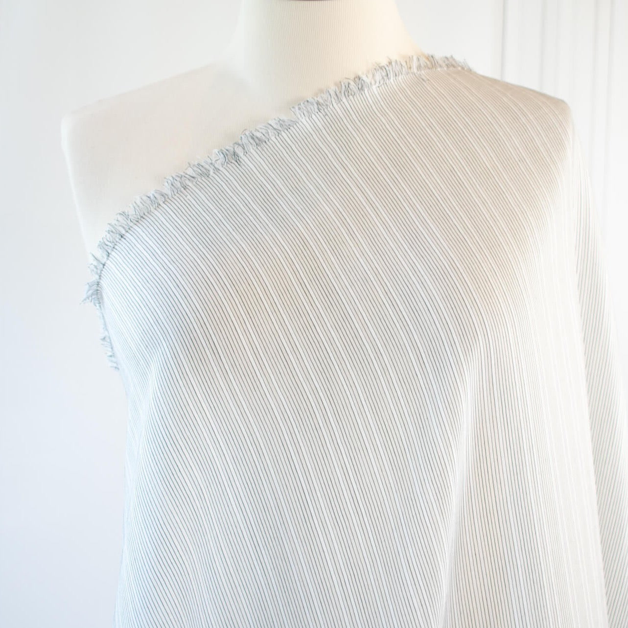 Light and airy Italian voile is soft and ohh so summery! Can you just picture yourself in a loose fitted unbuttoned shirtdress as a gorgeous layering piece over a cami and ankle length jeans.  This will definitely take your summer holiday up a notch!  Perfect for summer dresses, skirts and tops. The thin horizontal black stripes and bright white woven opaque stripes are set against a sheer white voile.  Fabric on dress form.