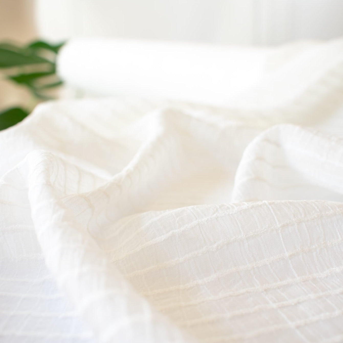 You will be dreaming of summer in this soft, sheer designer woven fabric. This feels so good against the skin, a must have for summer dresses and tops. Gorgeous sewn up in a loose fitting garment or take advantage of the stripe and go for a bias cut! Fabric has a white jacquard horizontal stripe against a white sheer background. Close up image.
